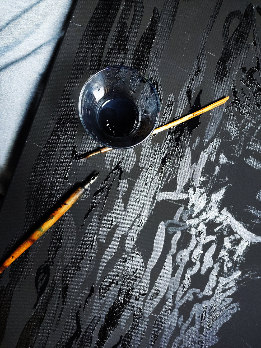 Close-up photo of vintage calligraphy dip pens resting on top of a dark acrylic painting with detailed feather textures