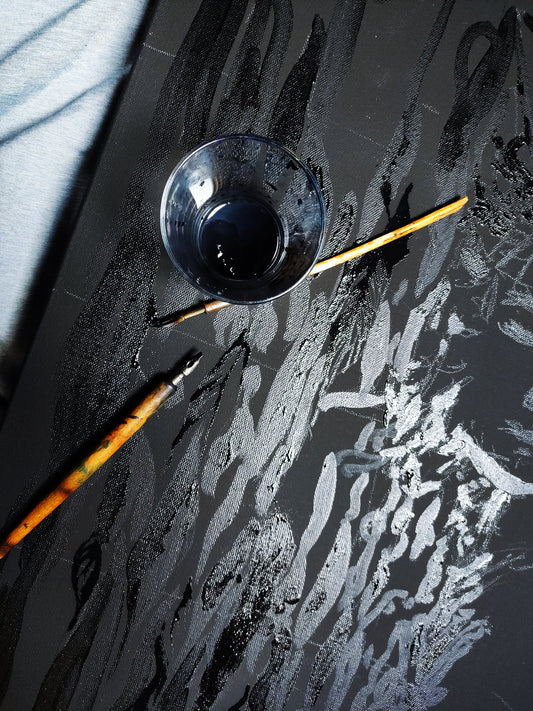 Close-up photo of vintage calligraphy dip pens resting on top of a dark acrylic painting with detailed feather textures