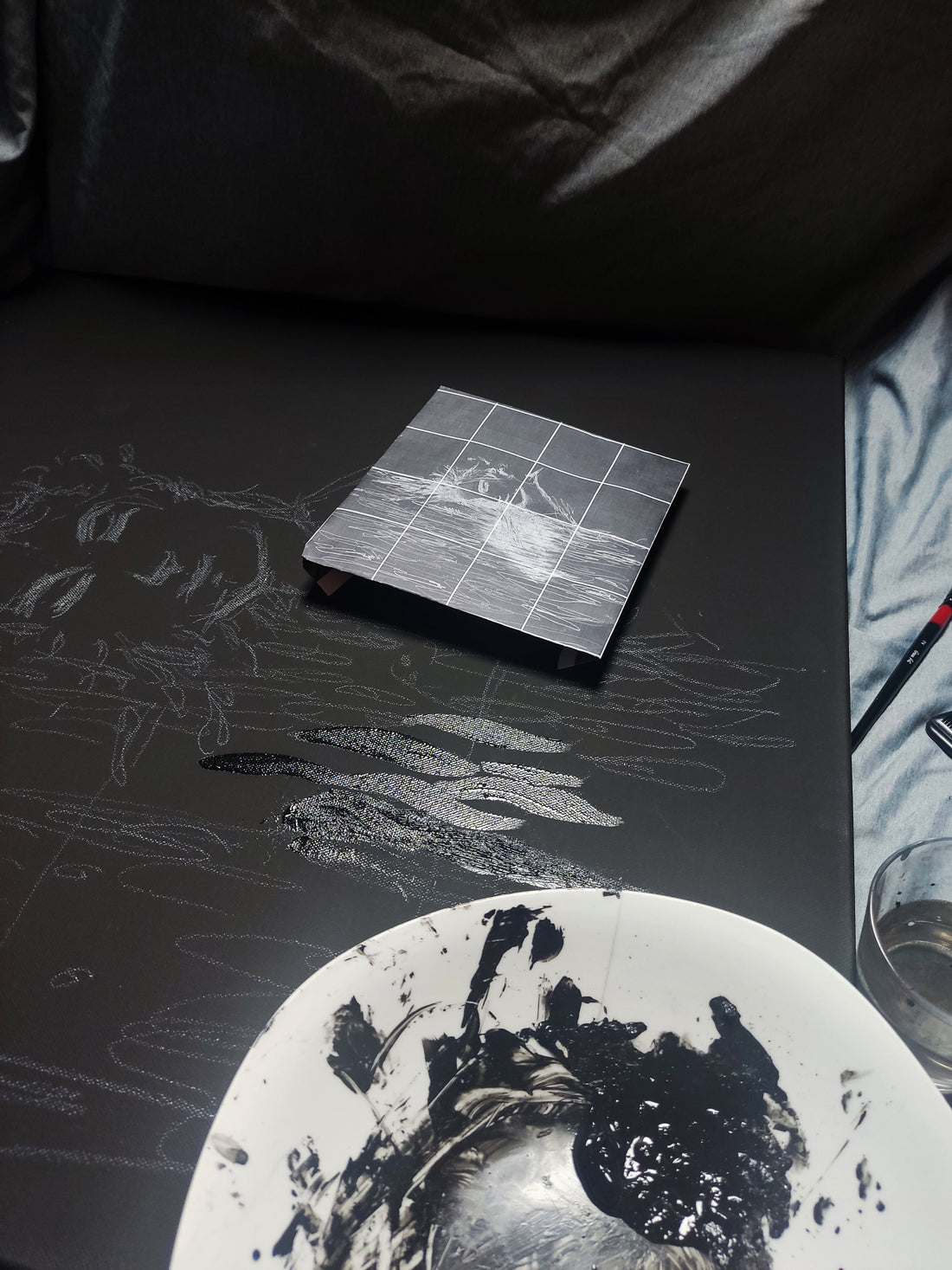 Palette knife applying glossy acrylic paint on a matte black canvas in an attic studio space